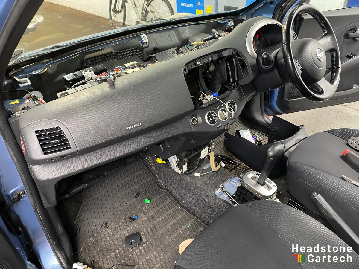 Vehicle dashboard partially disassembled during Apple CarPlay installation showing exposed mounting brackets and wiring