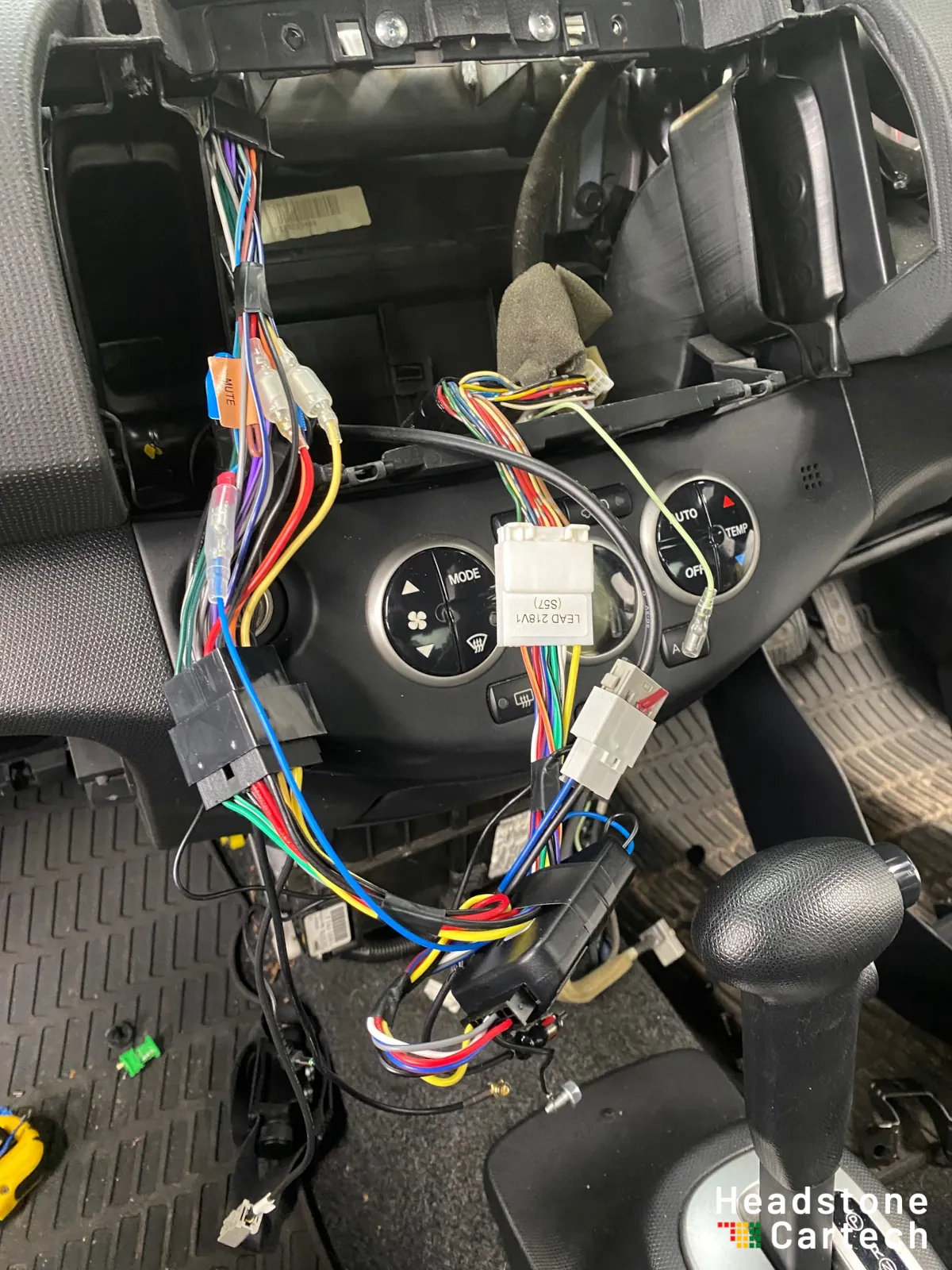 Close-up of professional wiring harness conversion work during Apple CarPlay installation showing multiple connectors and adapter looms
